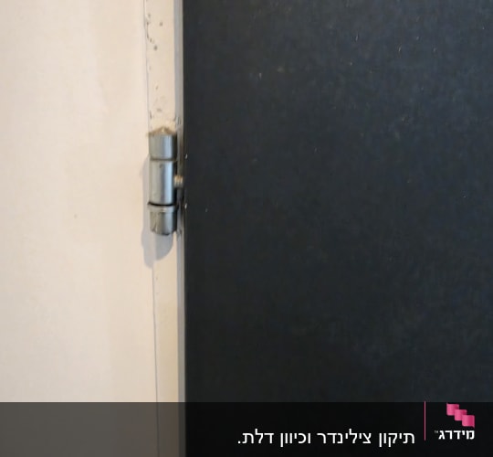תקריב של ציר מתכתי בתחתית דלת